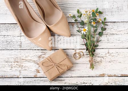 Anelli di nozze, fiori e scarpe su sfondo di legno Foto Stock