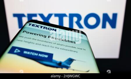 Smartphone con sito web della società aerospaziale statunitense Textron Inc. Sullo schermo di fronte al logo aziendale. Mettere a fuoco sulla parte superiore sinistra del display del telefono. Foto Stock