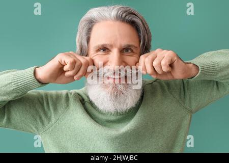 Uomo anziano felice in maglia maglione su sfondo verde Foto Stock