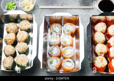 Take away sushi rotoli in contenitori, philadelphia rotoli e gamberi cotti set, su sfondo di pietra grigia Foto Stock