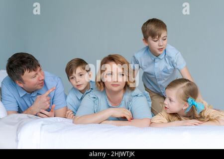 Felice famiglia caucasica si trovano in camera da letto e sorridere. Vestiti di blu stanno divertendosi insieme. Genitori e figli due figli e una figlia carina Foto Stock