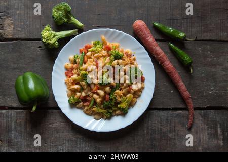 La popolare pasta di macaroni italiana cotta in salsa servita in un piatto bianco. Foto Stock