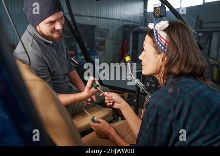 Bel maschio ingegnere e bella donna con cacciavite in mani in hangar Foto Stock