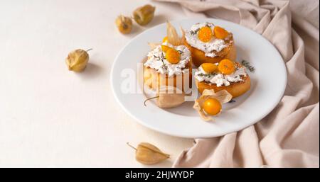 Crostini di ricotta con frutti di Physalis su un piatto bianco Foto Stock