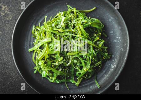 Wakame verde. Insalata di alghe su piatto nero. Vista dall'alto. Foto Stock