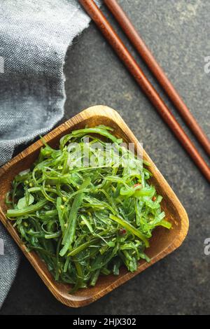 Wakame verde. Insalata di alghe in ciotola di legno. Foto Stock