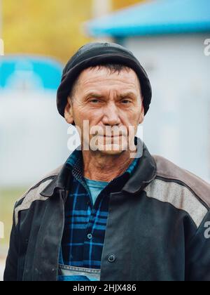 Ritratto petto-alto dell'uomo di lavoro. Vero e proprio costruttore di lavoratori stanchi in abiti da lavoro si trova sulla strada e guarda direttamente in macchina fotografica. Saldatrice vera e propria di 50-60 anni Foto Stock