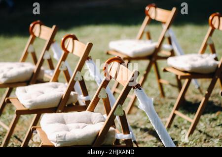 Sedie si trovano sull'erba verde nell'area della cerimonia nuziale, ombrelloni bianchi appendono sulle sedie. Foto Stock