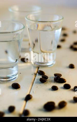 Sambuca in bicchieri e chicchi di caffè su sfondo bianco Foto Stock