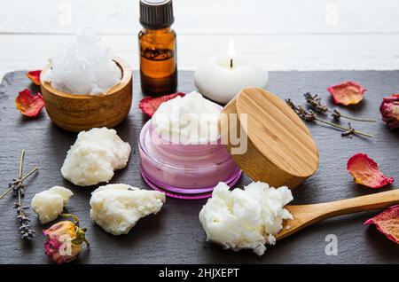 Fare bodywhip anche noto come burro corpo, crema idratante per la cura della pelle. Ingredienti su sfondo legno: Burro di karité, olio di cocco solido, oli essenziali. Foto Stock