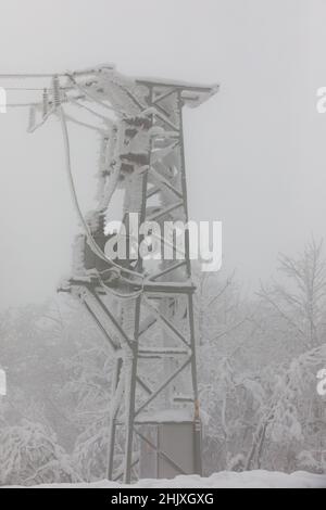 Piloni della linea di alimentazione congelati. Gelo su cavi e tralicci ad alta tensione. Inverno in montagna. Foto Stock