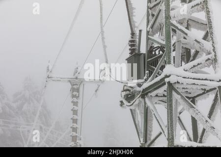 Piloni della linea di alimentazione congelati. Gelo su cavi e tralicci ad alta tensione. Inverno in montagna. Foto Stock