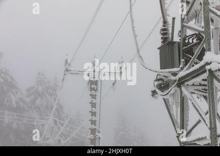 Piloni della linea di alimentazione congelati. Gelo su cavi e tralicci ad alta tensione. Inverno in montagna. Foto Stock