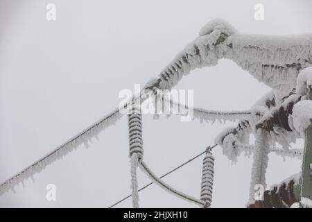 Piloni della linea di alimentazione congelati. Gelo su cavi e tralicci ad alta tensione. Inverno in montagna. Foto Stock