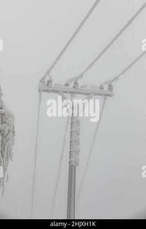 Piloni della linea di alimentazione congelati. Gelo su cavi e tralicci ad alta tensione. Inverno in montagna. Foto Stock