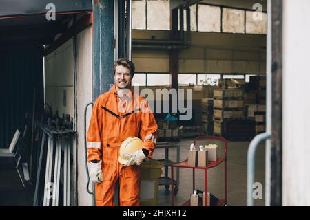 Ritratto di uomo sorridente blu-colletto lavoratore in uniforme in magazzino Foto Stock