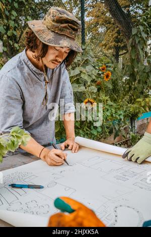 Ambientalista maschile che si disegna su un piano al tavolo Foto Stock