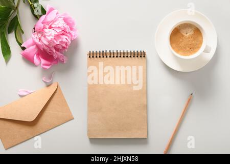 Fantasia femminile con sketchbook artigianale, tazza di caffè, fiore rosa di peonia su sfondo grigio. Spazio di copia. Vista dall'alto, piatto. Foto Stock