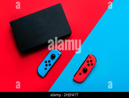 Nintendo Switch console videogiochi con Nintendo due Joy-Cons su sfondo rosso e blu Foto Stock