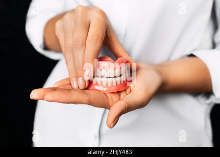 Il dentista tiene le dentarie nelle sue mani. Protesi dentaria nelle mani del medico primo piano. Vista frontale della dentiera completa. Odontoiatria concetto Foto Stock