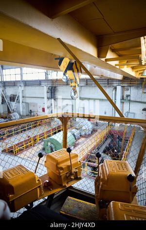 Vista dalla cabina dell'operatore della gru. Carroponte giallo a righe nere con ganci presso l'impianto petrolchimico. Iscrizioni sulle caselle Foto Stock