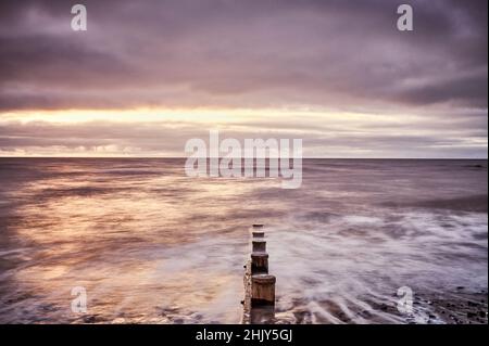 Mare che entra su groyne di legno Foto Stock