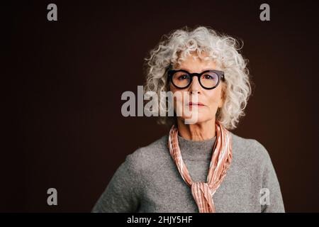 Ritratto di donna anziana fiduciosa in studio Foto Stock