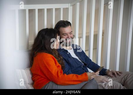 Felice coppia eterosessuale utilizzando lo smartphone in camera da letto Foto Stock