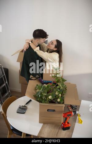 Coppia eterosessuale che abbraccia mentre si alza in salotto Foto Stock