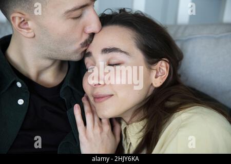 L'uomo affettuoso bacia la fronte della ragazza in camera da letto a casa Foto Stock