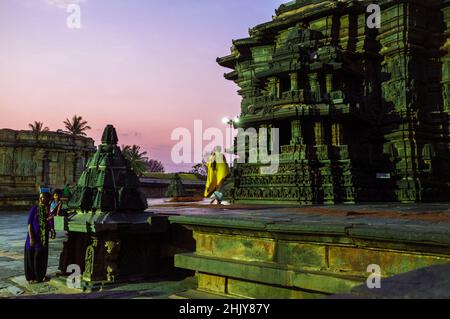 Belur, Karnataka, India : Tempio di Chennakeshava del XII secolo. Un sacerdote indù cammina al tramonto sulla piattaforma jagati per circumambulazione (pradakshina-p Foto Stock