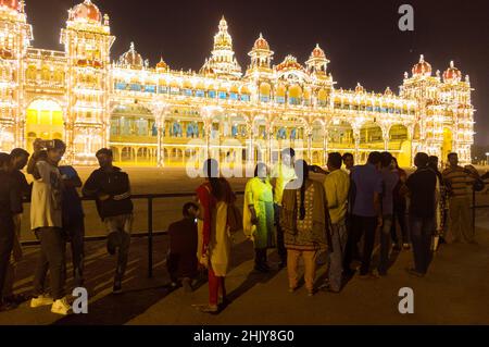 Mysore, Karnataka, India : i visitatori si trovano di notte accanto al Palazzo Mysore Maharaja illuminato. Foto Stock