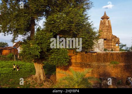 Khajuraho, Madhya Pradesh, India : Villagers camminano nella campagna intorno alla parte del tempiale di Vamana del gruppo orientale del Patrimonio Mondiale dell'UNESCO S. Foto Stock