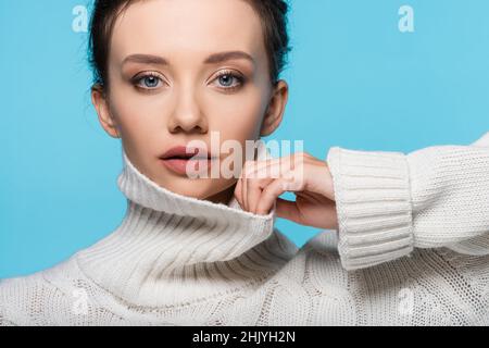 Giovane modello a contatto colletto di maglione in maglia isolato su blu Foto Stock