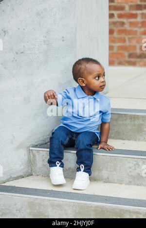 Un ragazzo carino afroamericano di un anno di età quasi prescolare con grandi occhi sorridenti e guardando via con spazio copia Foto Stock