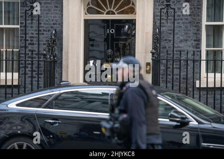 Downing Street, Londra, Regno Unito. 1 febbraio 2022. Un ufficiale di polizia Metropolitano armato passa la porta d'ingresso a Downing Street 10 durante la riunione di gabinetto mattina, una macchina ministeriale parcheggiata all'esterno. Credit: Malcolm Park/Alamy Live News. Foto Stock