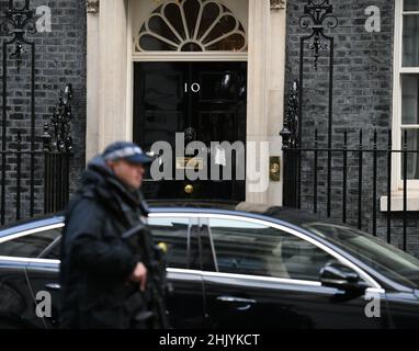 Downing Street, Londra, Regno Unito. 1 febbraio 2022. Un ufficiale di polizia Metropolitano armato passa la porta d'ingresso a Downing Street 10 durante la riunione di gabinetto mattina, una macchina ministeriale parcheggiata all'esterno. Credit: Malcolm Park/Alamy Live News. Foto Stock