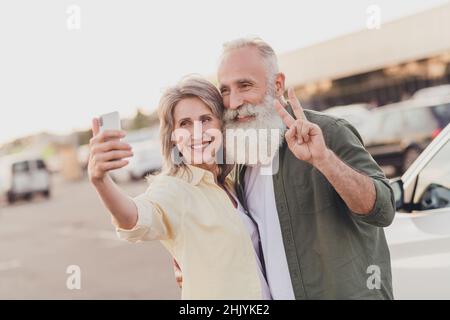 Foto di pensionato pensionato in pensione sposato persone moglie marito grigio capelli vecchia coppia selfie v-segno parco carta fuori fuori fuori in città Foto Stock