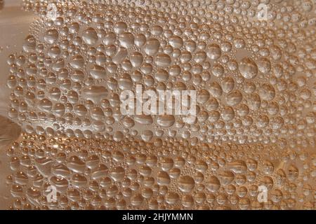 Primo piano di gocce d'acqua su una superficie marrone sotto le luci per texture Foto Stock