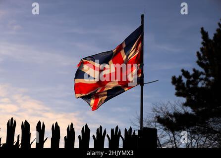 Il sole sorge sopra Belfast orientale mentre la bandiera dell'Unione soffia nel vento. Foto Stock