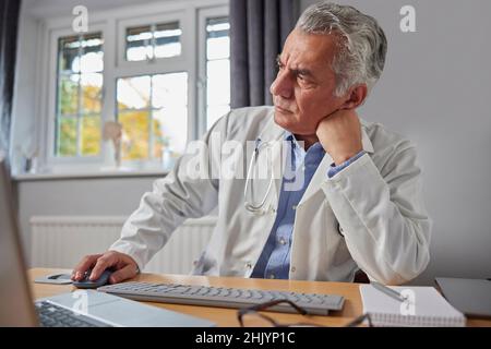 Dottore stressato e sopravlavorato in cappotto bianco alla scrivania in ufficio Foto Stock