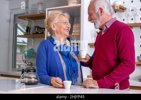 La coppia anziana era deliziosa e beveva caffè in cucina, sorridendo e parlando l'una con l'altra. Foto Stock