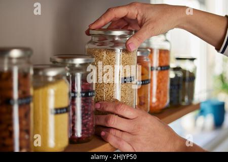 Donna che riutilizza vasi di vetro per conservare cibo essiccato vivere stile di vita sostenibile a casa Foto Stock