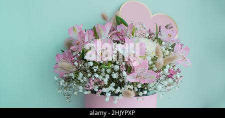 Striscione con delicato bouquet di gigli rosa, rose bianche, gypsofiles. Sfondo turchese. Cuore rosa, spazio di copia. Foto Stock