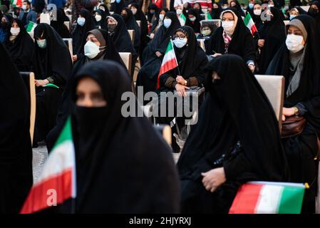 Teheran, Iran. 01st Feb 2022. Una donna velata che indossa una maschera protettiva per il viso tiene una bandiera iraniana mentre si siede di fronte alla tomba del leader iraniano, Ayatollah Ruhollah Khomeini, durante il primo giorno della vittoria dell'anniversario della rivoluzione islamica nel cimitero di Behesht-e Zahra nel sud di Teheran (Foto di Sobhan Farajvan/Pacific Press) Credit: Pacific Press Media Production Corp./Alamy Live News Foto Stock