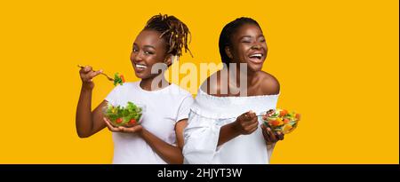 Ritratto di sorridente Black Ladies Holding Plate con insalata Foto Stock