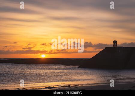 Due persone guardano l'alba a Cullercoats Foto Stock