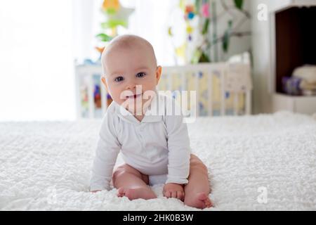 Little baby boy, bimbo, gioca in casa con il giocattolo di peluche nel letto in camera da letto Foto Stock