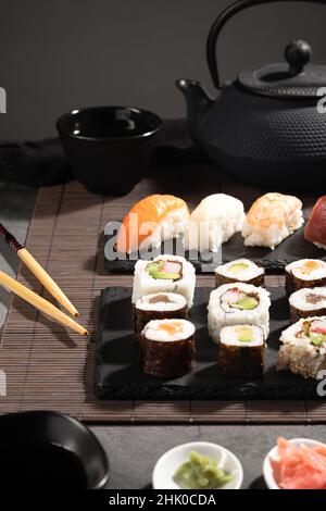 Primo piano di sushi fresco su sfondo scuro. Set di sushi e tè giapponese. Formato verticale. Foto Stock