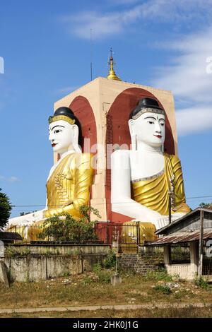 Le quattro facce Buddha seduto indietro a schiena (ognuno ha vestiti ed espressioni differenti), Buddha Kyaikpun, Bago, Myanmar Foto Stock